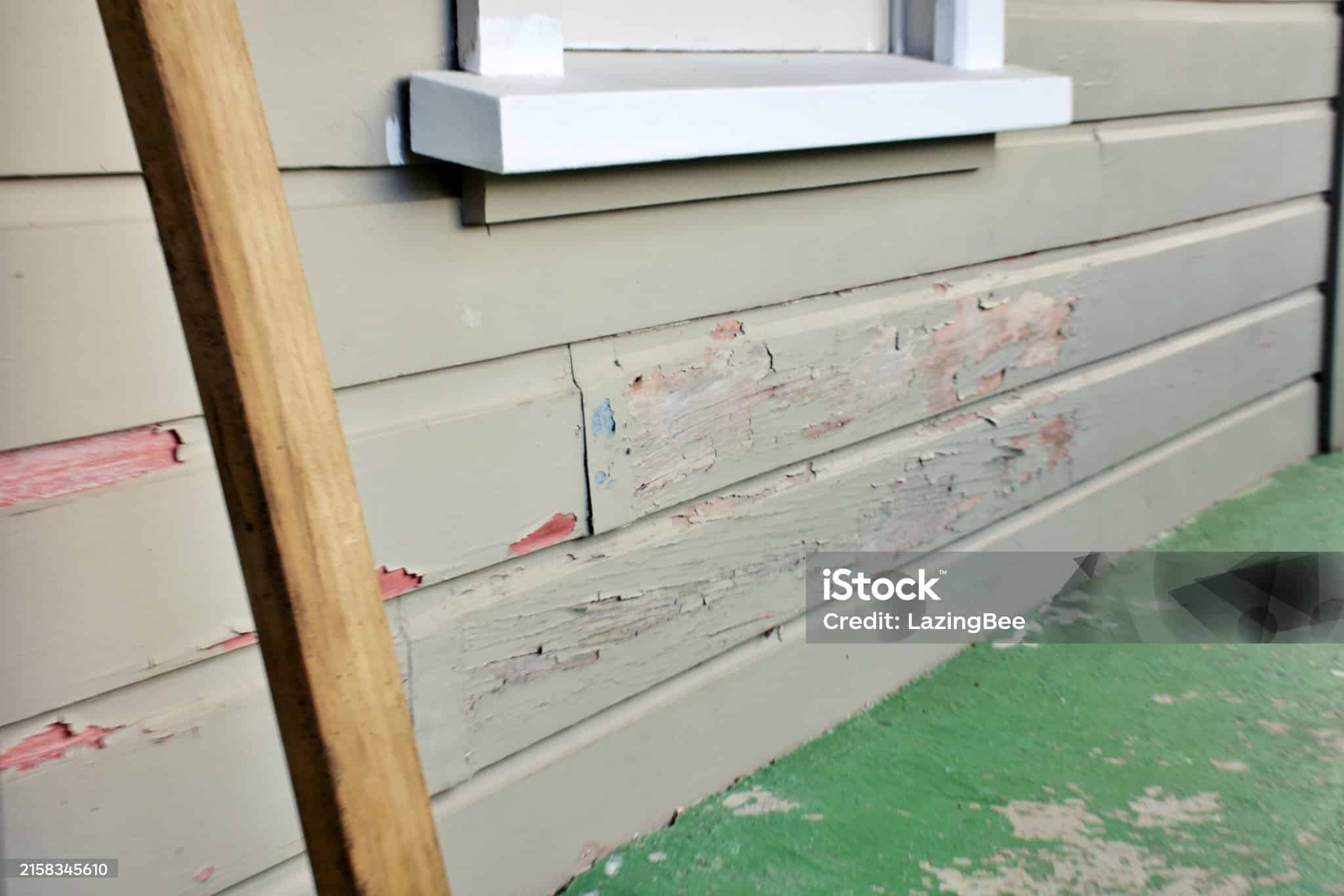 Old paint lifts and peels on a weatherboard / clapboard clad house.